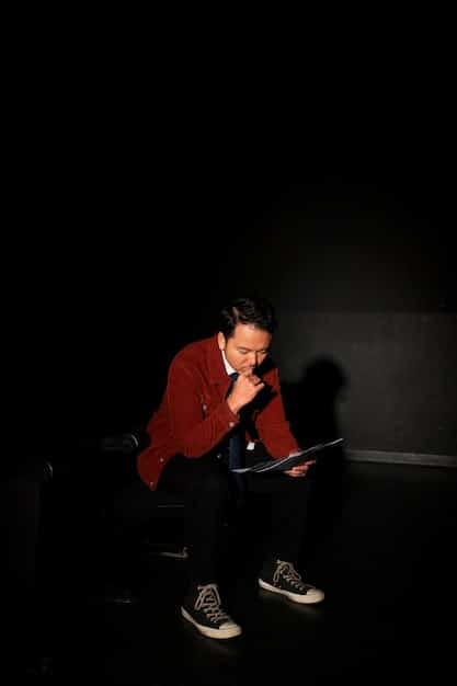 A film critic sitting in a dark screening room, illuminated by the light of the movie screen. They are taking notes intently, wearing glasses and showing a focused expression. Various notes and a pen are visible on their notepad.