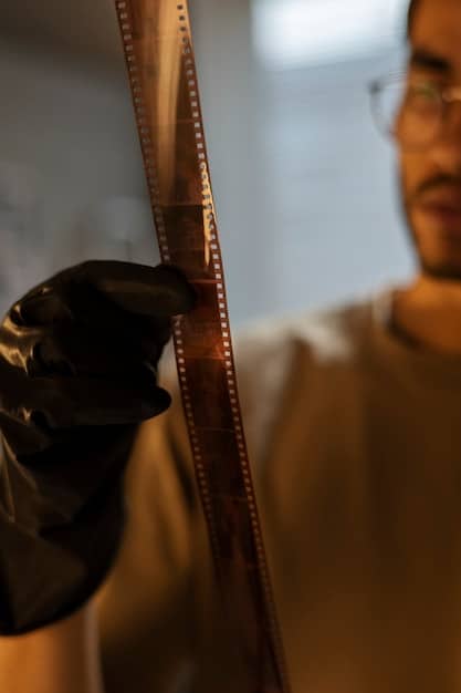 Close-up of a film editor's hands meticulously splicing film strips together on a vintage editing machine. Light shines through the film, highlighting the detailed work.