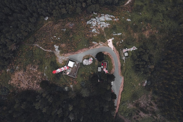 A drone shot of a film crew setting up equipment on a narrow, winding road in a remote mountain pass, illustrating the challenges of accessibility and logistical planning in location scouting.