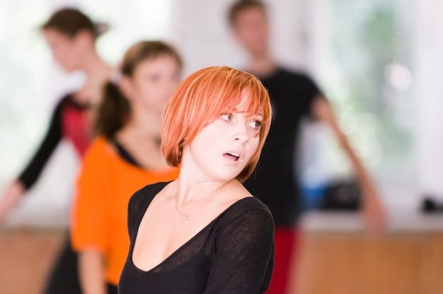 A close-up shot of a choreographer intensely watching dancers during a rehearsal. The choreographer's expression shows deep concentration and focus.